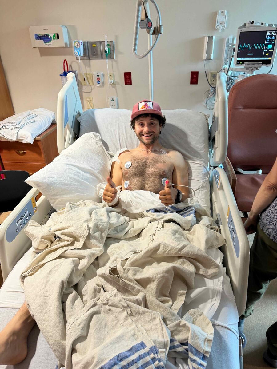 Elliott Saslow in a hospital bed after the crash, giving two thumbs up