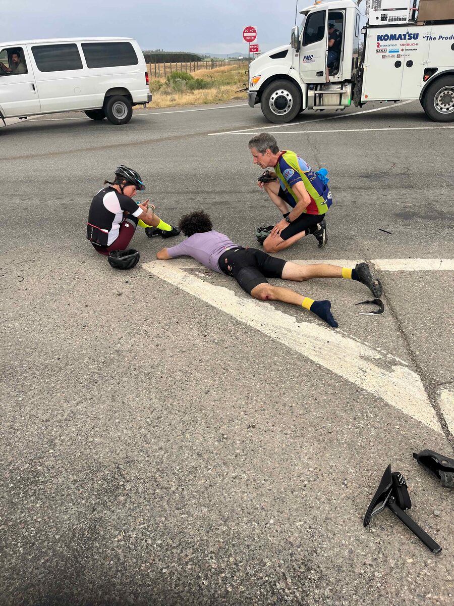 Cyclists attending to an injured rider in the roadway after the crash